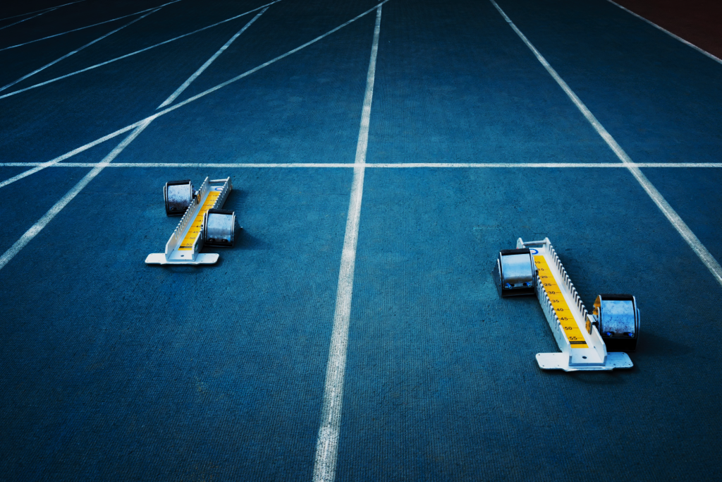 Two athletics starting blocks set on a blue running track, viewed from above before a race